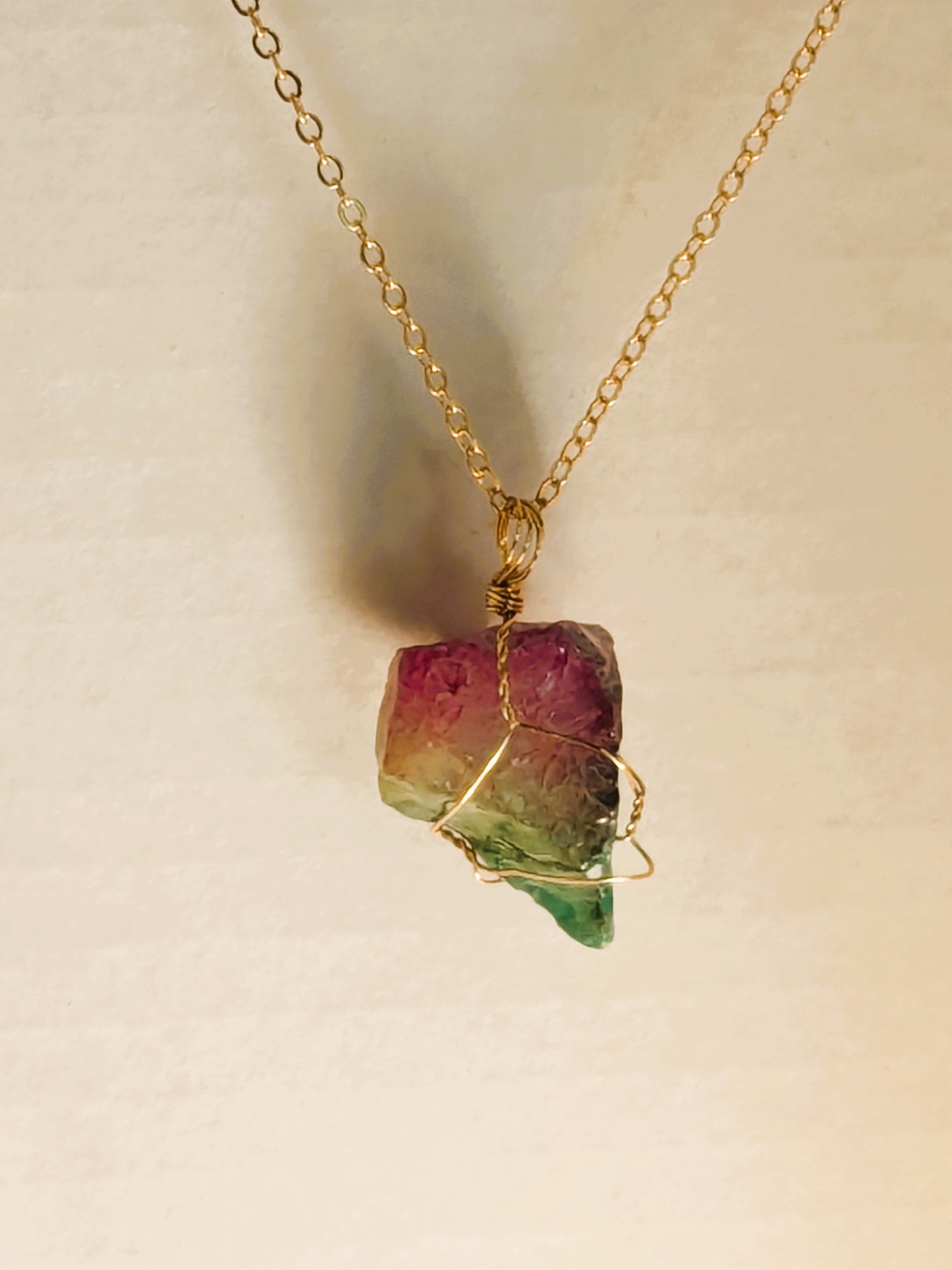 Gold chain necklace with tri-color crystal pendant: pink top, yellow middle, green bottom, wrapped in gold wire.